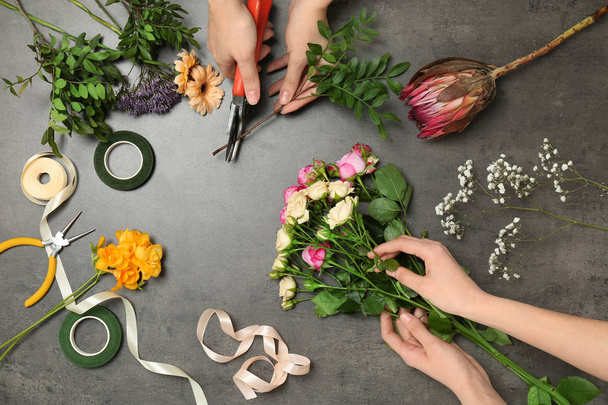 Female florists making beautiful bouquet at table, top view - Fotografie, Obrázek