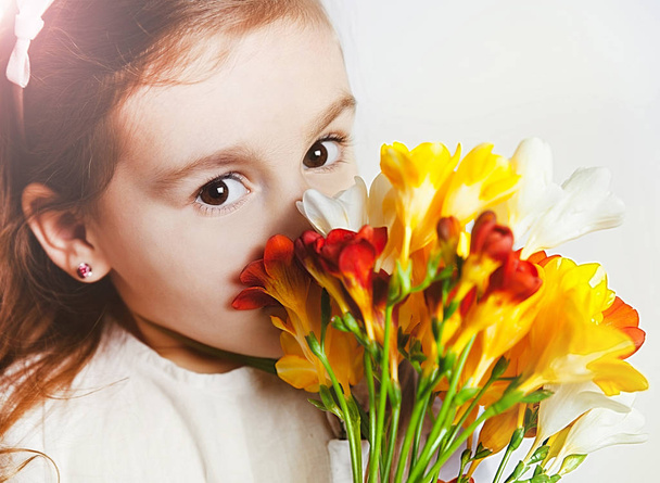 Cute redhead girl smelling spring flowers freesia. close up - Zdjęcie, obraz