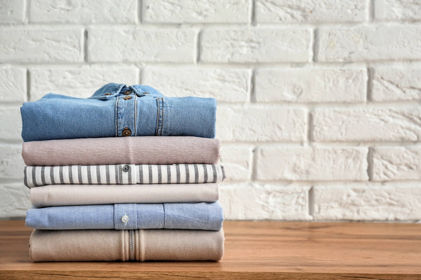 Stack of clothes on table near brick wall - Fotoğraf, Görsel