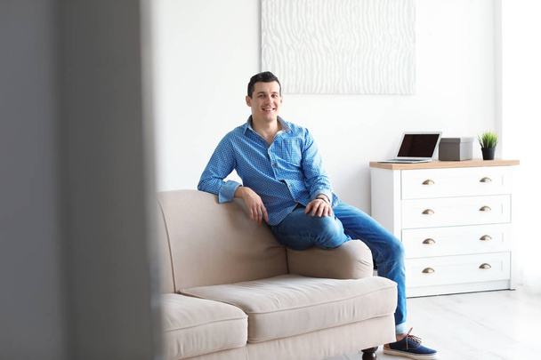 Portrait of confident man on sofa at home - Fotó, kép