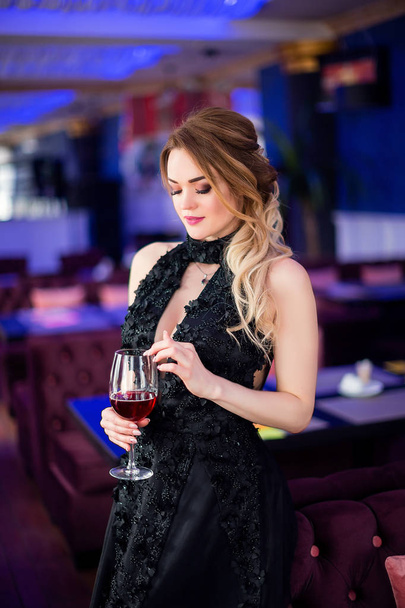 beautiful sensual woman in elegant clothes sitting in cafe, drinking vine - 写真・画像
