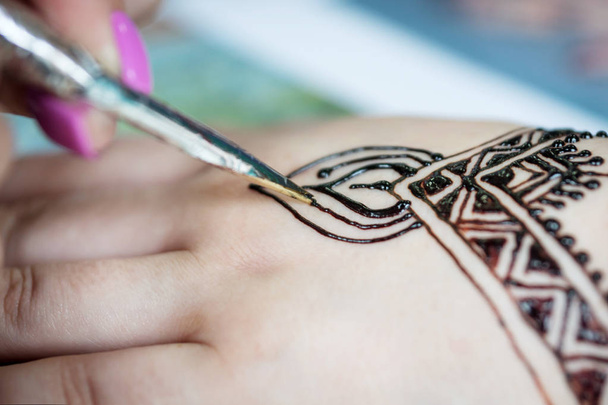 woman mehendi artist painting henna on the hand - 写真・画像