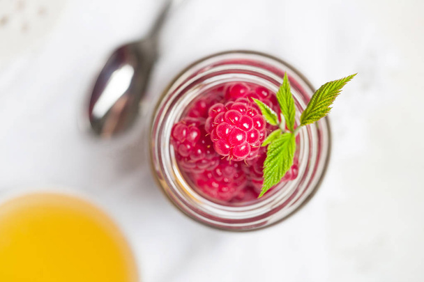 Raspberries in glass jar with leaves. Flat lay, top view - Photo, Image