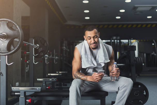 Black bodybuilder using mobile phone at gym - Photo, Image