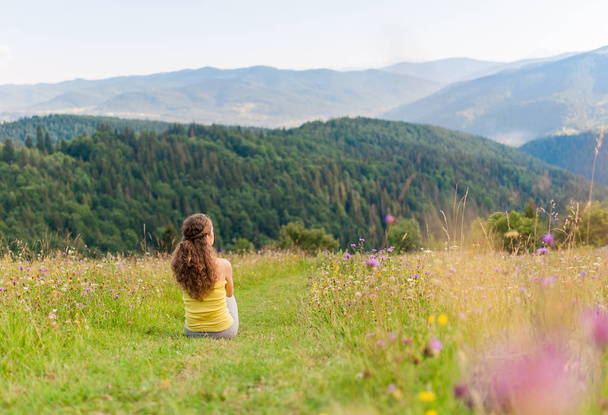Sport Woman Traveler sitting and resting on the mountains top. Mountains landscape on background. - Foto, imagen
