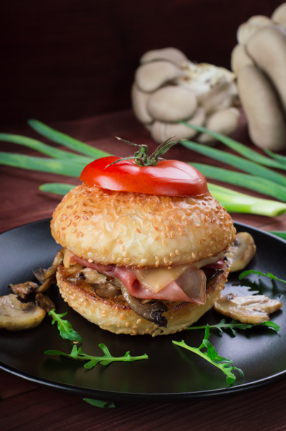 Hamburger met gebakken champignons, ham, uien en kaas op rustieke achtergrond - Foto, afbeelding