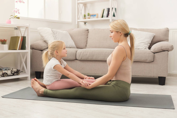 Mother and little daughter doing yoga together - Фото, зображення