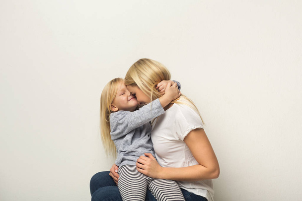 Happy mother and daughter embracing at studio - 写真・画像