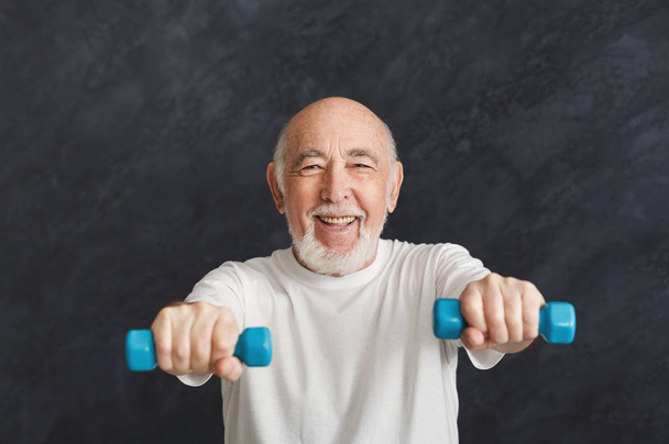 Vanhempi mies tekee liikuntaa käsipainoilla
 - Valokuva, kuva