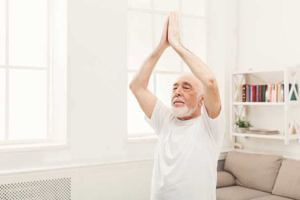 Hombre mayor practicando yoga de pie en padmasana
 - Foto, imagen