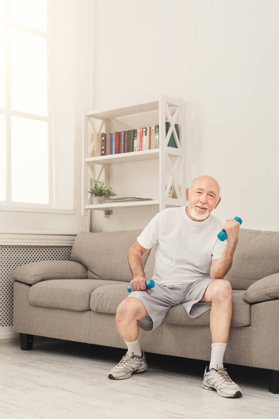 Senior man making exercise with dumbbells - Photo, Image