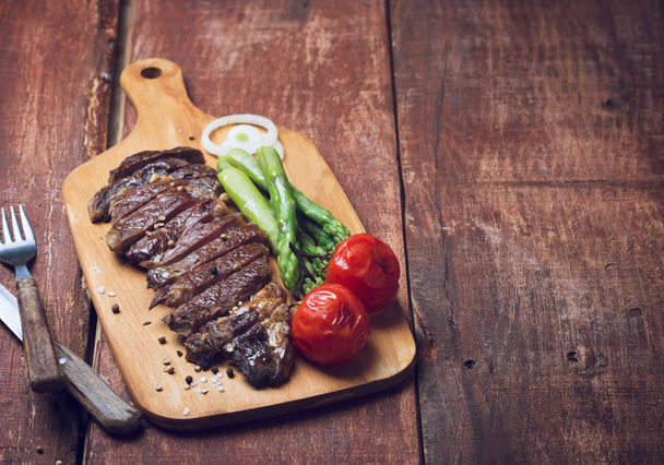 Grilled beef steak with asparaguas and tomatoes on a wooden rustic background - Photo, Image