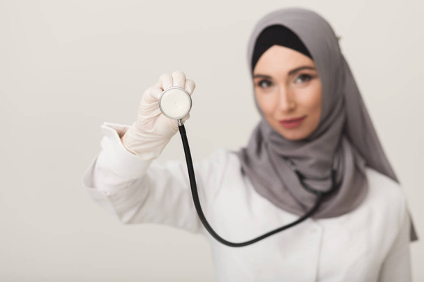 Mulher em hijab mostrando estetoscópio no fundo do estúdio
 - Foto, Imagem