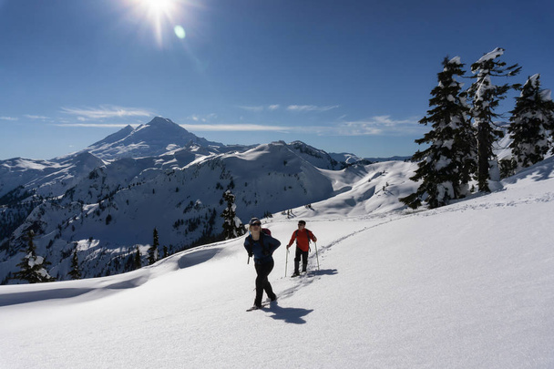 Adventurous man and woman are snowshoeing in the snow. Taken in Artist Point, Northeast of Seattle, Washington, United States of America. - Foto, immagini
