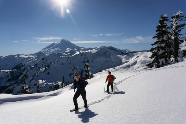 Adventurous man and woman are snowshoeing in the snow. Taken in Artist Point, Northeast of Seattle, Washington, United States of America. - Foto, immagini
