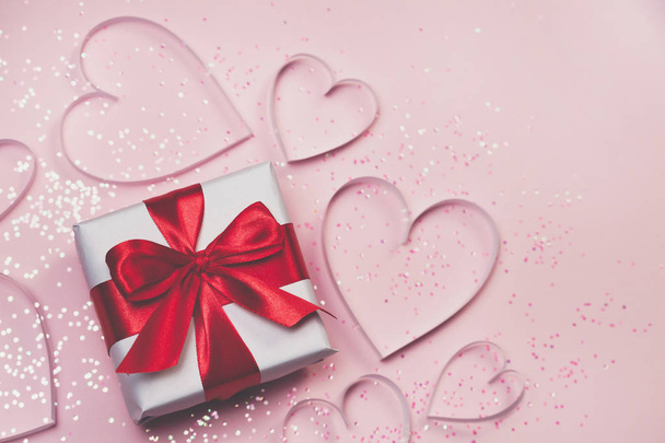 Gift box and paper hearts with sparkling glitter on pink background. Romantic st. Valentine's day concept of greetings. Top view, flat lay - Foto, afbeelding