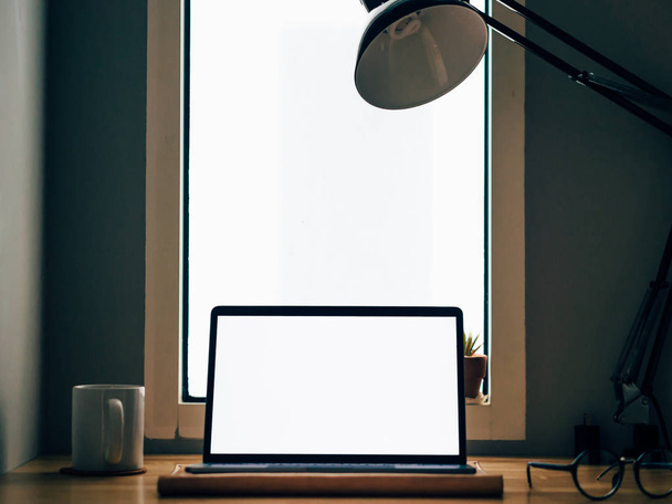 Laptop with white empty screen on wooden desk in the room of freelance office. - Foto, imagen