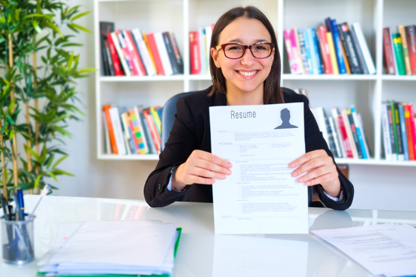 Young smiling cheerful woman holding her resume - Photo, Image