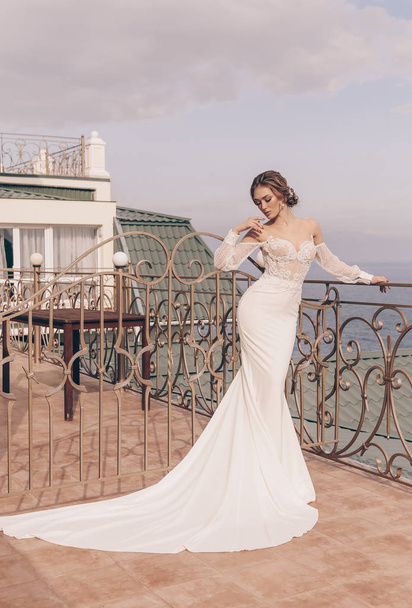 fashion  photo of beautiful  woman with blond hair in luxurious wedding dress and accessories posing outdoor, with sea and mountains view - Φωτογραφία, εικόνα