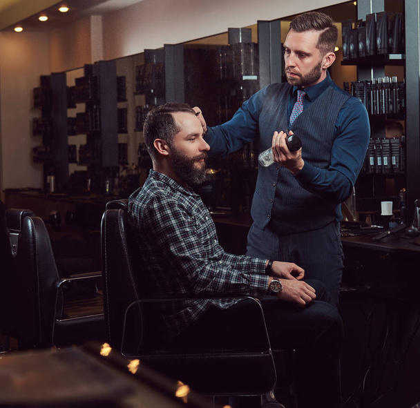 Barbier professionnel travaillant avec un client dans un salon de coiffure. Coupe de cheveux pour hommes dans un salon de coiffure
. - Photo, image