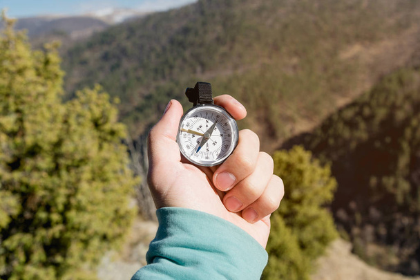 Close-up A mans hand holds a pocket compass against the backdrop of mountains and woods. The concept of outdoor navigation - Fotó, kép