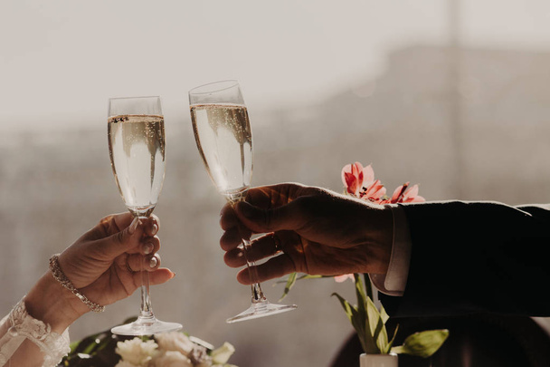 Woman`s and man`s hands hold glasses of alcoholic beverage, clink glasses, celebrate their wedding day. Leisure, celebration, drinks, holidays and people concept - Fotoğraf, Görsel