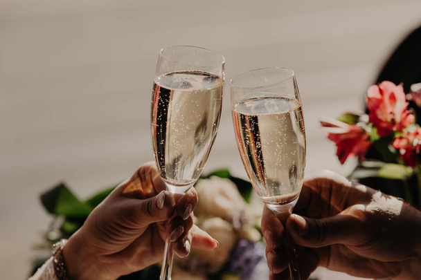 Bride and groom toast and clink glasses with champagne, celebrate wedding in restaurant. Engaged young couple celebrate this special occasion. - Photo, Image