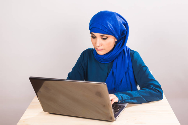 Уверенность довольно мусульманская женщина работает на ноутбуке. Концепции бизнеса и финансов
. - Фото, изображение