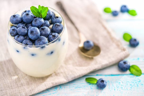 Μπολ με blueberries γιαούρτι σε ξύλινα φόντο, το top view - Φωτογραφία, εικόνα