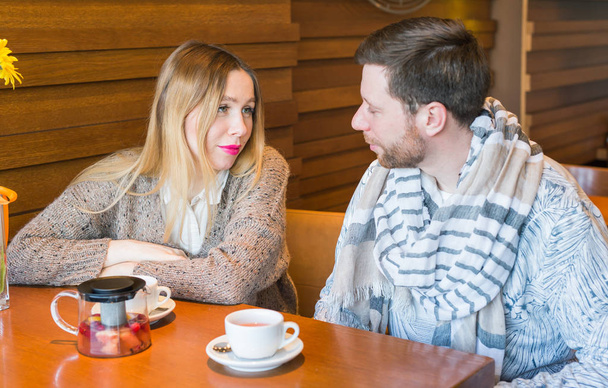 Щаслива молода пара говорить і п'є каву і посміхається, сидячи в кафе
. - Фото, зображення