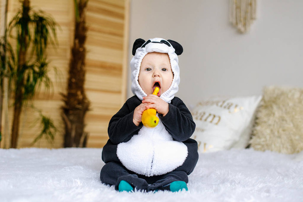 Aranyos kis medve fiú jelmez Panda ül ágyas szobában - Fotó, kép