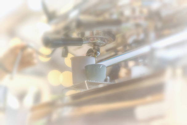 Close-up fresh espresso pours into porcelain cup, hand of professional barista. Coffee culture and professional coffee making, service and catering concepts. Light background - Φωτογραφία, εικόνα