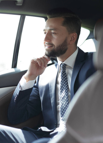 Smiling business man sitting in the back seat of a car - Foto, Bild