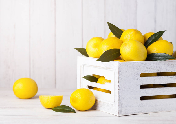 Fresh raw lemons in white wooden box with leaves - Fotografie, Obrázek