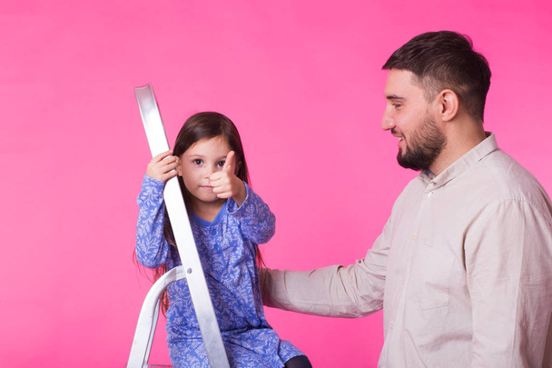 Father and her little daughter over pink background. Adult man and baby girl are happy - Foto, immagini