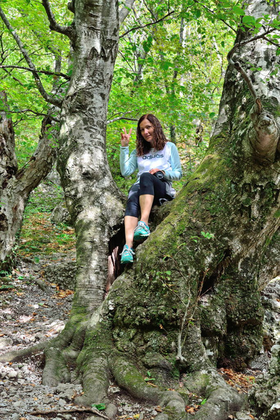 Girl sitting on a tree near the trail in the gorge haphal - Fotoğraf, Görsel