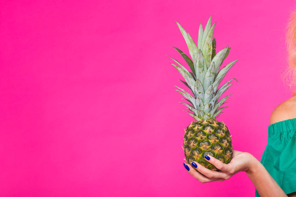 Zbliżenie dłoni womans gospodarstwa ananas na różowym tle, z tło. Lato, diety i zdrowego stylu życia koncepcja - Zdjęcie, obraz
