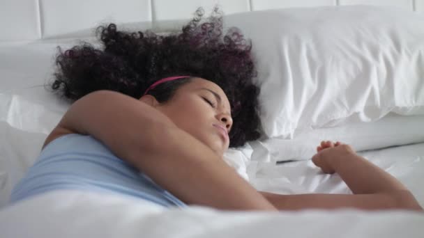 Dość młoda African American kobieta budzi się w łóżku - Materiał filmowy, wideo