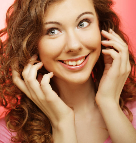 young beautiful woman with curly hair over pink background - Foto, Imagem