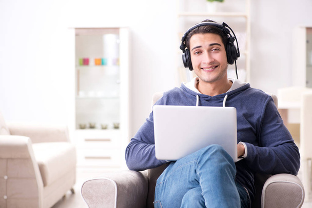 Νεαρός όμορφος άντρας ακούει μουσική με ακουστικά - Φωτογραφία, εικόνα