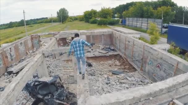 Νεαρός άνδρας περπατά μέσα από τα ερείπια. Κλιπ. Ένας άνδρας τρέχει μέσα από τα εγκαταλειμμένα ερείπια, αεροφωτογραφία - Πλάνα, βίντεο