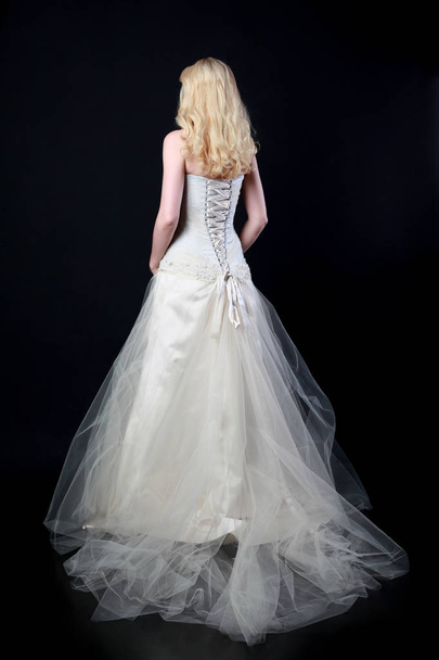 full length portrait of model wearing white bridal ball gown, standing pose on black background. - 写真・画像