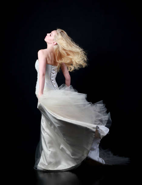 full length portrait of model wearing white bridal ball gown, standing pose on black background. - 写真・画像