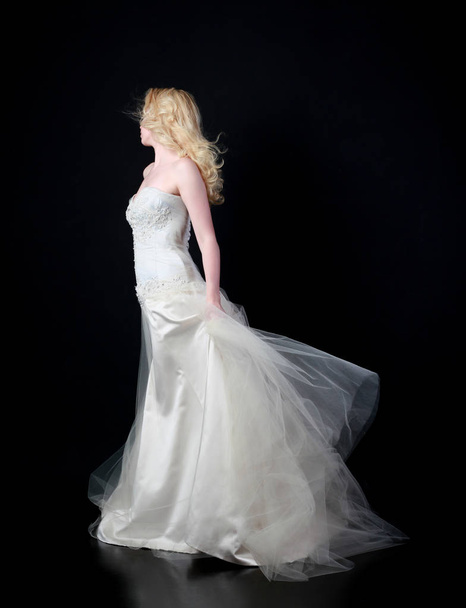full length portrait of model wearing white bridal ball gown, standing pose on black background. - Photo, Image