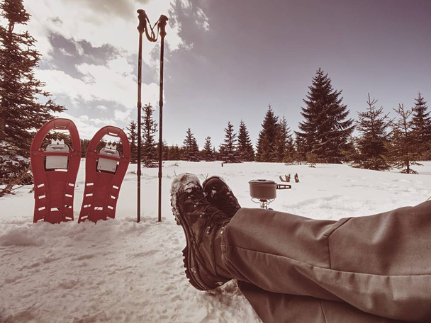 Rode sneeuwschoenen en trekking Polen klaar in de sneeuw, wintervakantie in de bergen. Winter hoogteweg in besneeuwde landschap. Nise zonnig weer. - Foto, afbeelding