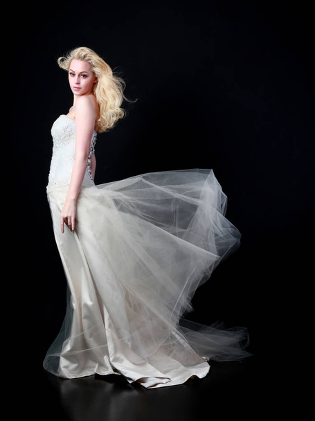 full length portrait of model wearing white bridal ball gown, standing pose on black background. - Foto, imagen