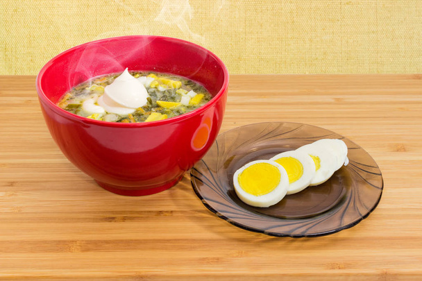 Soupe à l'oseille avec oeuf et crème sure dans un bol rouge
 - Photo, image