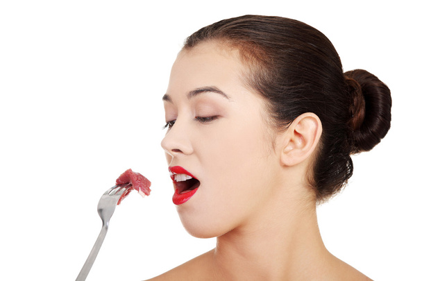 Young beautiful woman eating raw meat. - 写真・画像