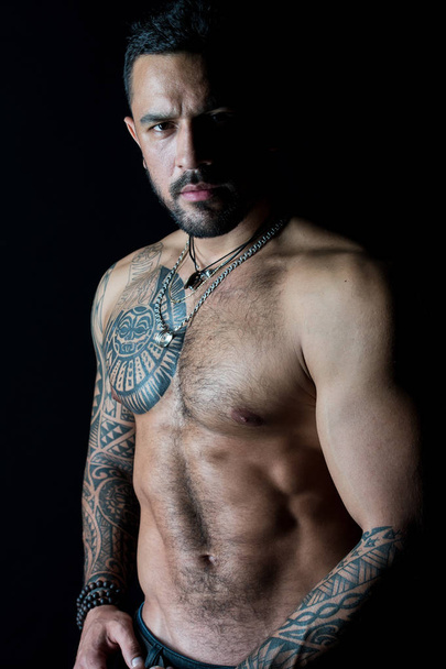 Fit model with tattoo art on skin. Bearded man with tattooed chest. Macho with sexy bare torso. Sportsman or athlete with stylish beard and hair. Sport and fitness. Strength and motivation. - Photo, image