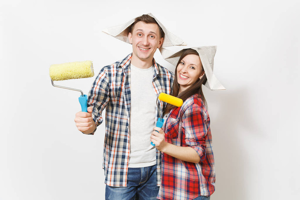 Young happy woman, man in casual clothes holding paint rollers for wall painting. Couple isolated on white background. Instruments, accessories for renovation apartment room. Repair home concept. - Fotó, kép